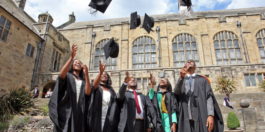 Proud graduates of Bangor University throw their mortar boards into the air in celebration.