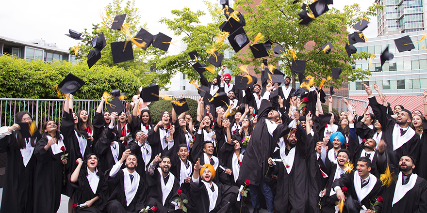 Graduates of Alexander College throw their mortar boards into the air, having achieved a university degree thanks to a transfer program with the college.